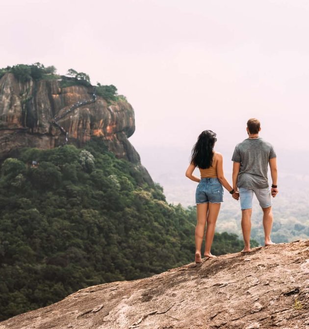 A couple in love on a rock admires the beautiful views. Boy and girl on the rock. A couple in love travels. Couple in Sri Lanka. Honeymoon in Asia. Man and woman in Sigiriya. Rear view pair